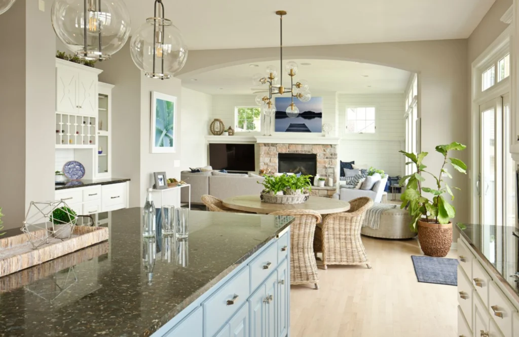 Coastal kitchen and dining area featuring blue cabinets, rattan furniture, and a modern design, emphasizing organization and style in a luxury home setting.