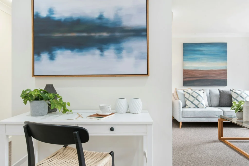 Home office setup featuring a white desk with a potted plant, decorative vases, and artwork on the wall, showcasing a modern and organized living space in Rockville, MD.