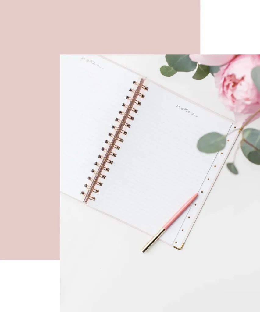 Notebook with blank pages and a pink pen, surrounded by greenery, symbolizing organization and productivity in time management.