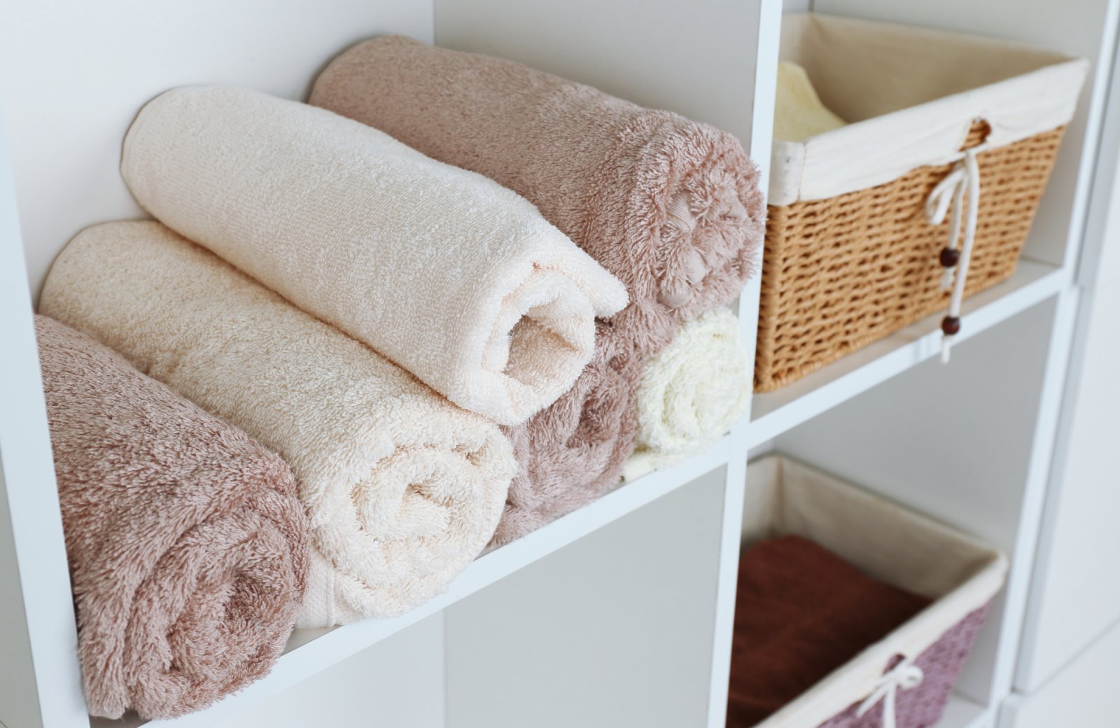 Organized linen closet with neatly rolled towels in soft colors, showcasing a clean and aesthetic arrangement, enhancing visual appeal and accessibility.
