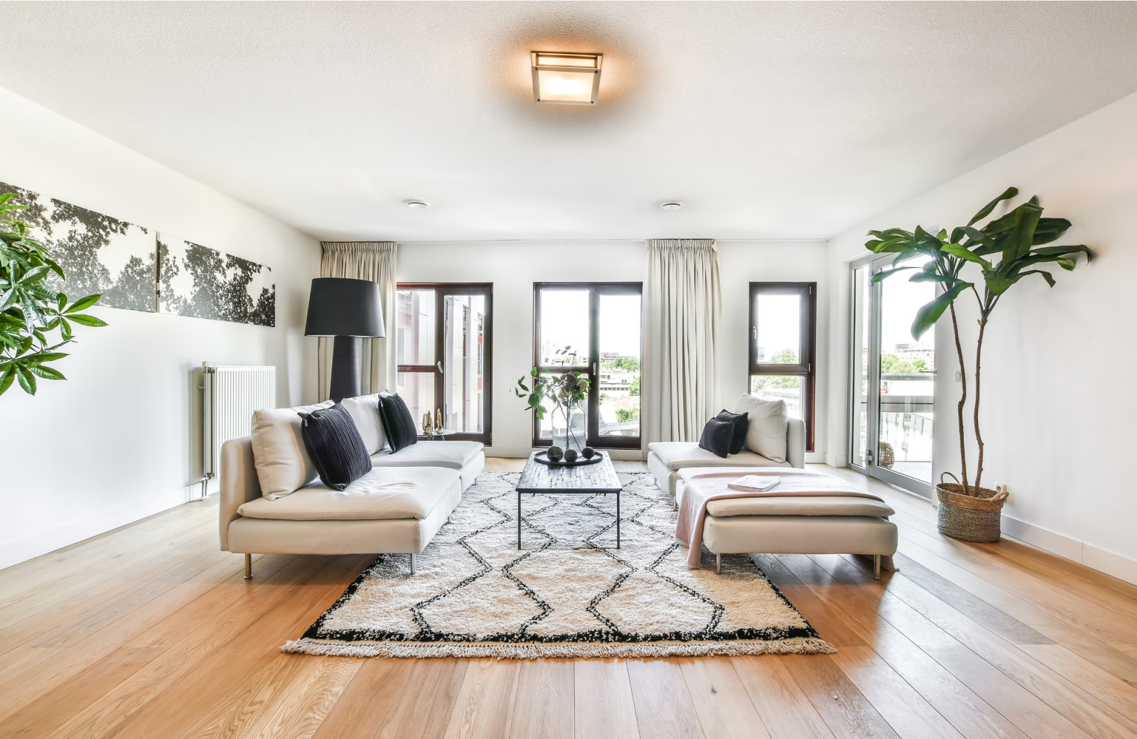 Bright, open living space featuring white sofas, a decorative area rug, and large windows, emphasizing a tranquil environment for emotional decluttering and organization.
