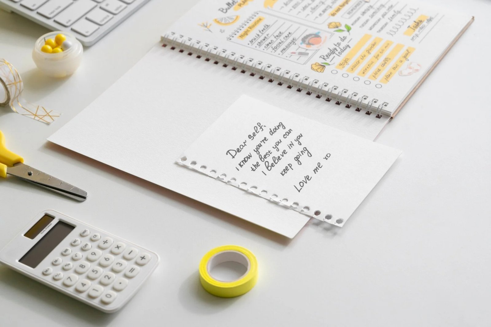 Colorful bullet journal with motivational note, scissors, calculator, and stationery, symbolizing organization and personal growth strategies in life coaching.